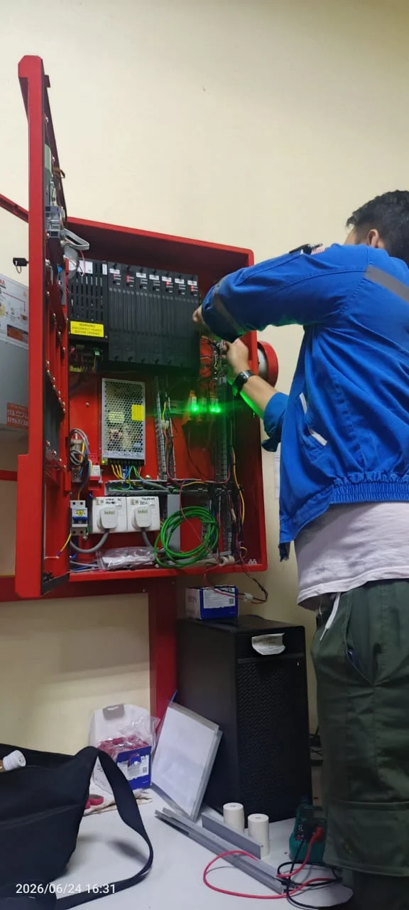 Technician troubleshooting a fire alarm control panel